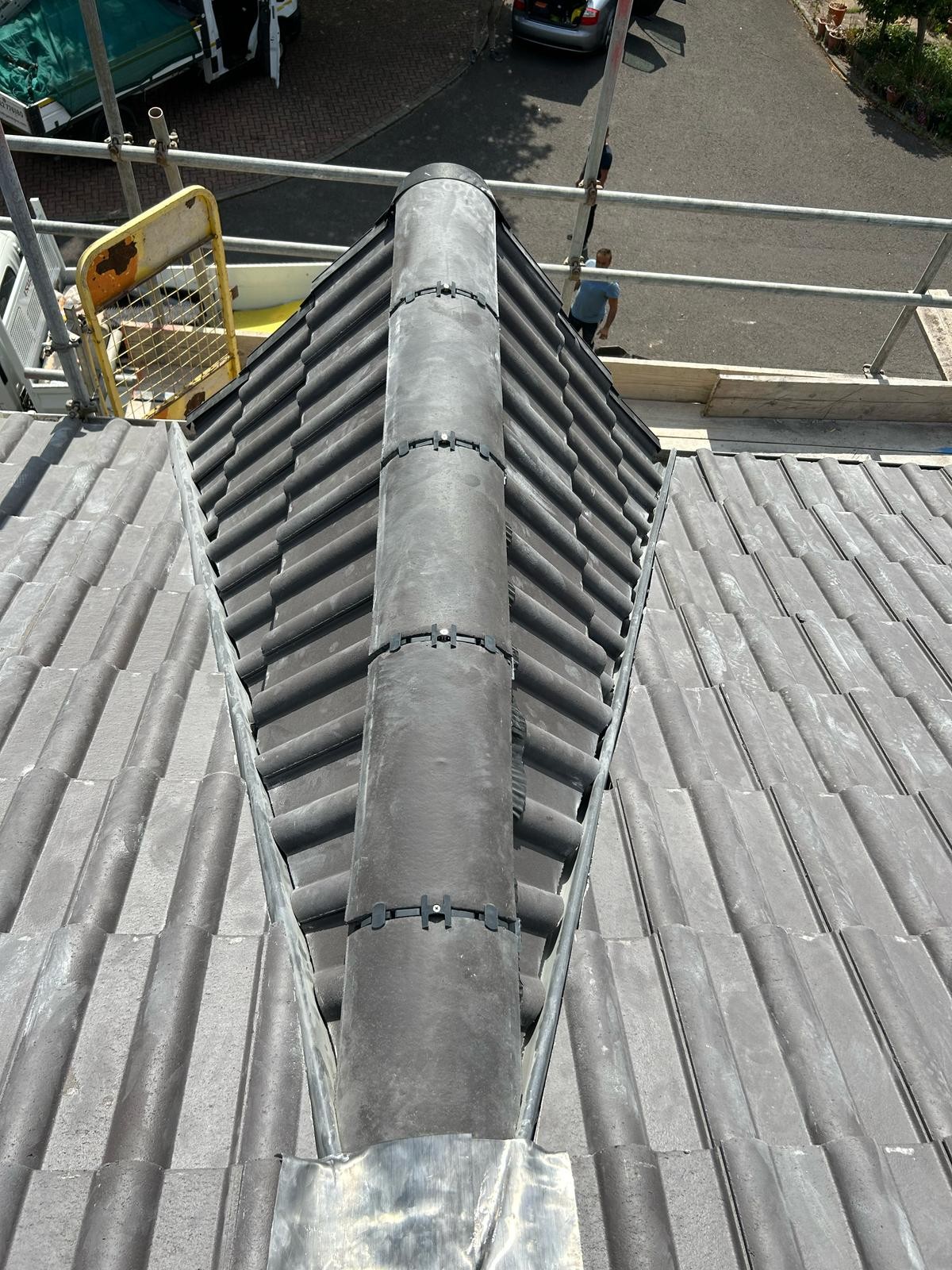 Newly bedded and pointed ridge tiles running along the apex of a re-tiled pitched roof