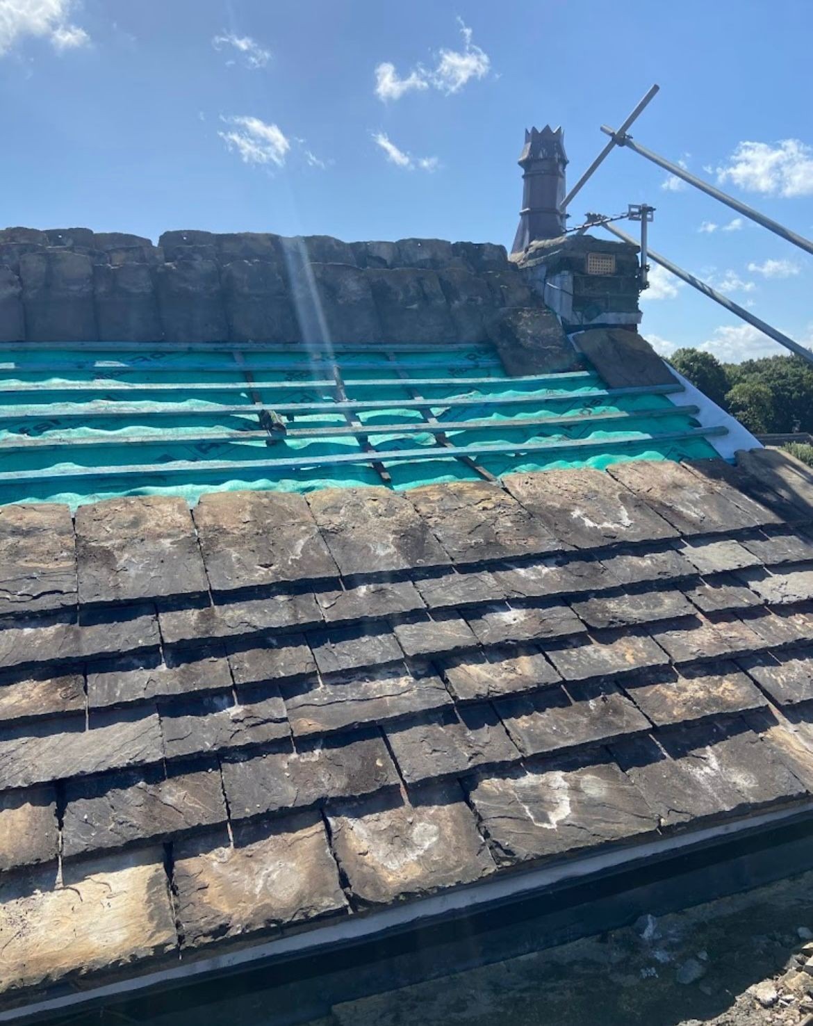 Reclaimed stone slates set out over fresh membrane during a slate re-roof